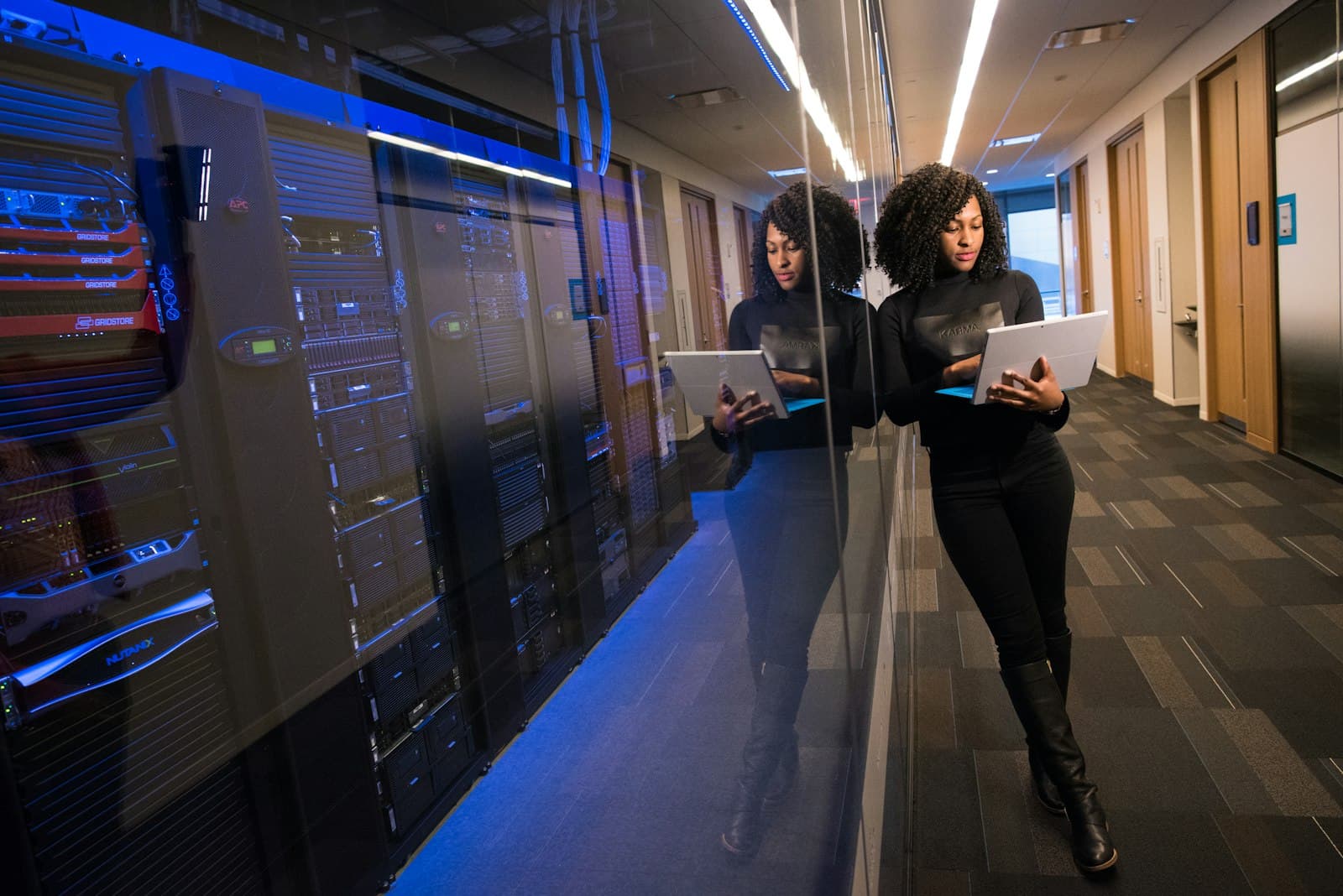 An engineer with a tablet beside server racks